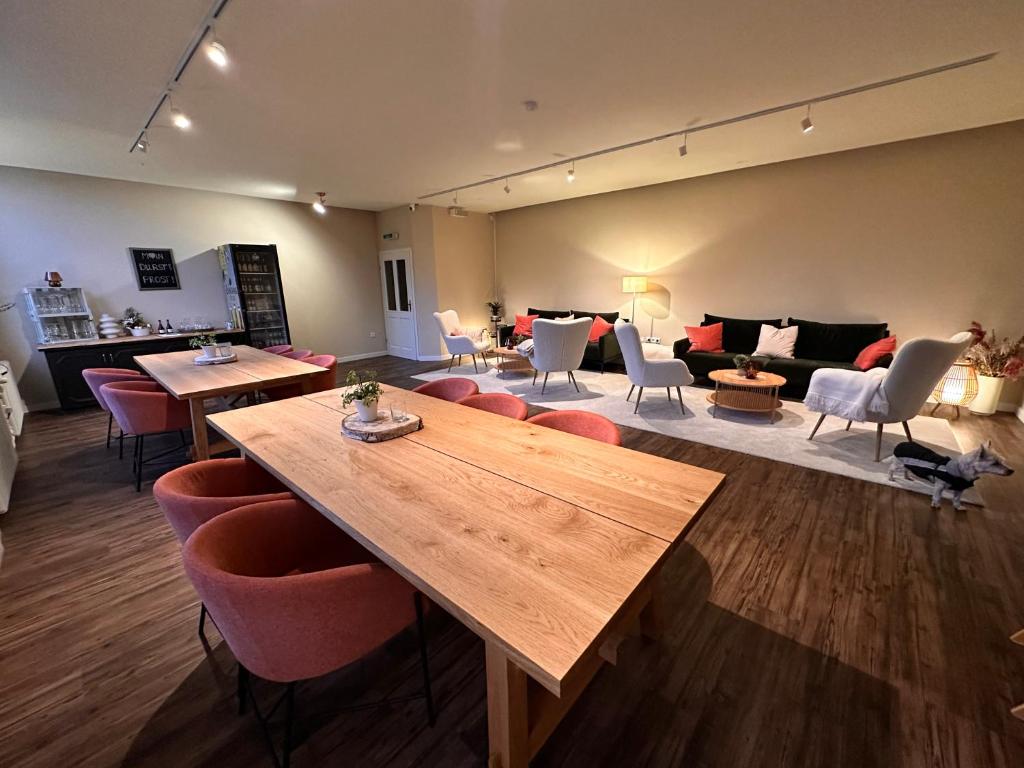 ヴァンガーラントにあるLandhotel Alte Schule - Hotel Garniのテーブル、椅子、ソファが備わる広い客室です。