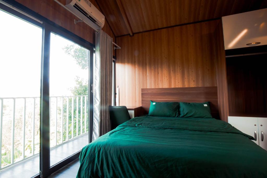 1 dormitorio con cama verde y ventana grande en AK Homestay - Motorbike Rental - Cao Bang City, en Cao Bằng