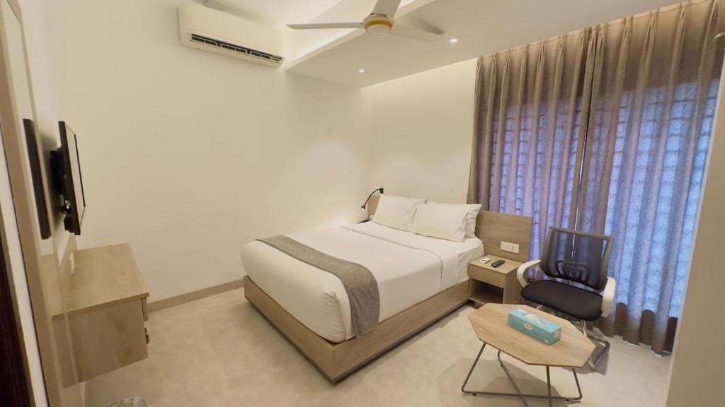 1 dormitorio con 1 cama, TV y silla en Priyo Nibash Stylish Residential Hotel, en Dhaka