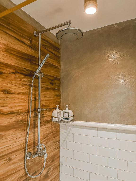 a shower stall in a bathroom with a wooden wall at Outpost Hostel - Coron in Coron