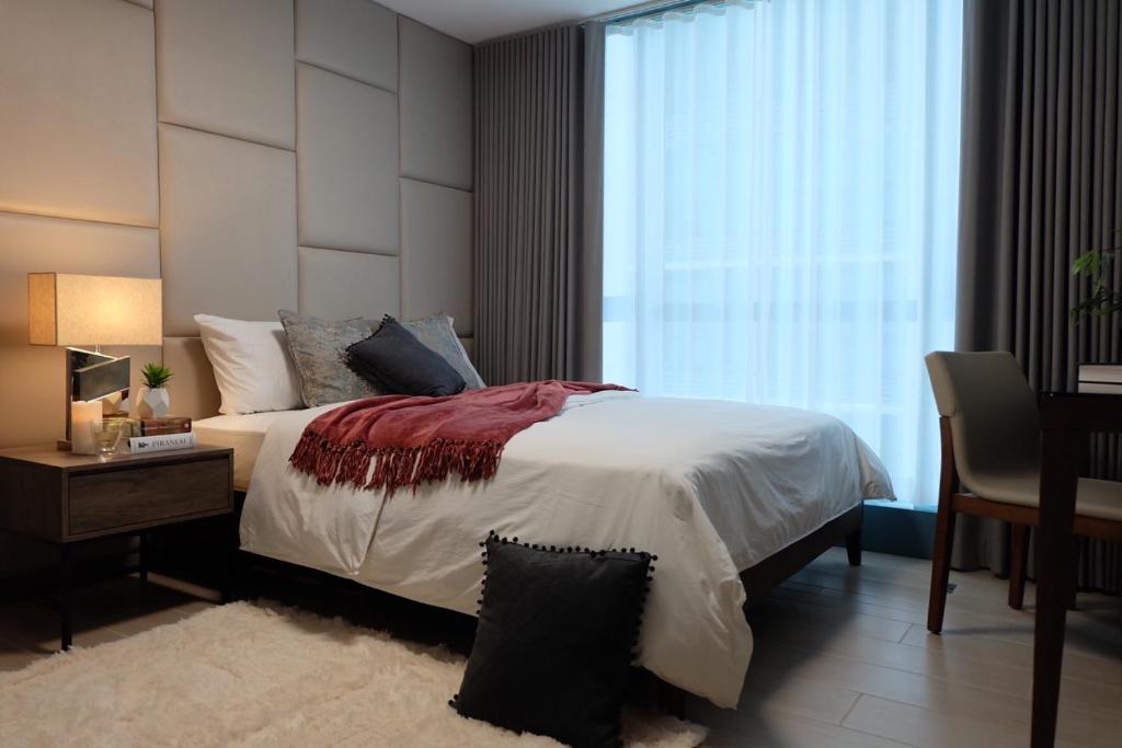 1 dormitorio con cama, escritorio y ventana en One Uptown Residence en Manila