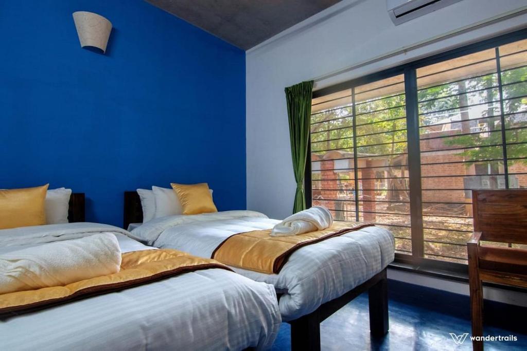 2 camas en una habitación con paredes azules y ventana en Paradise Le Tamarin, en Auroville
