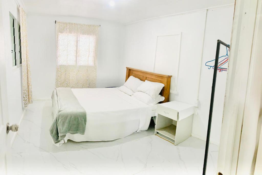 a white bedroom with a bed and a window at Tonga Cottage - Private Double Room Shared Facility in Folaha