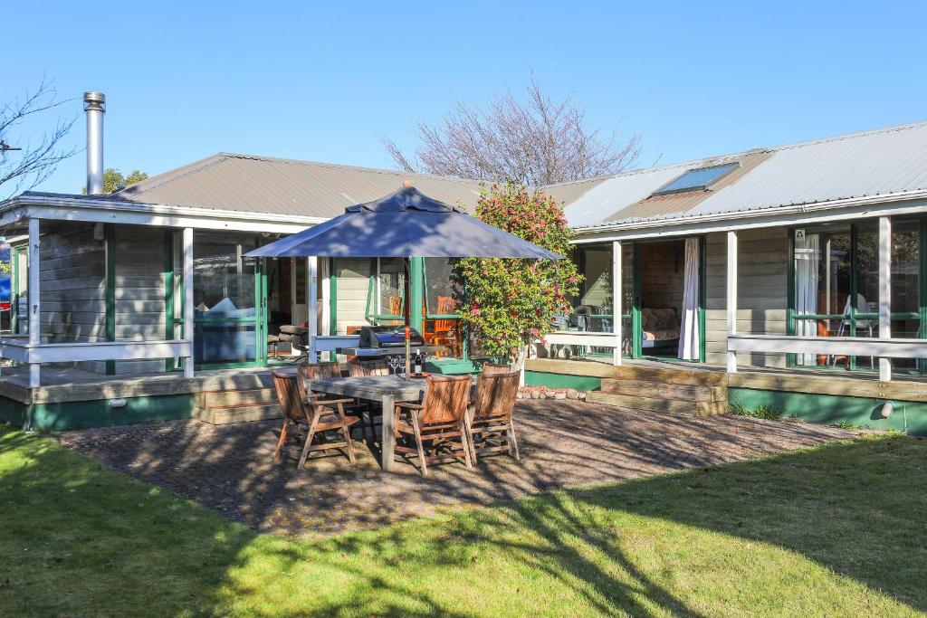 eine Terrasse mit einem Tisch, Stühlen und einem Sonnenschirm in der Unterkunft Five Mile Yay - Five Mile Bay Holiday Home in Taupo