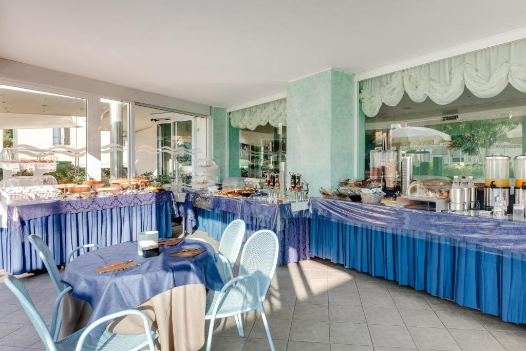un restaurant avec des tables et des chaises bleues devant un comptoir dans l'établissement Hotel Margareth, à Riccione