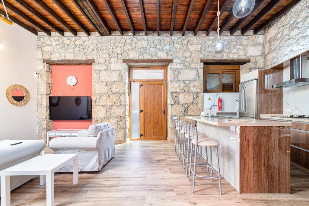 een keuken en een woonkamer met een bar en krukken bij CASA EL ROQUE in Telde