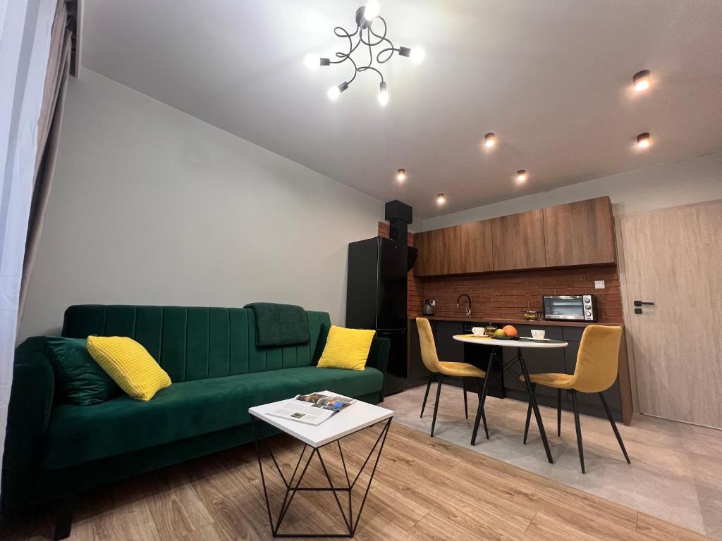 a living room with a green couch and a table at Apartamenty Marcina in Rzeszów
