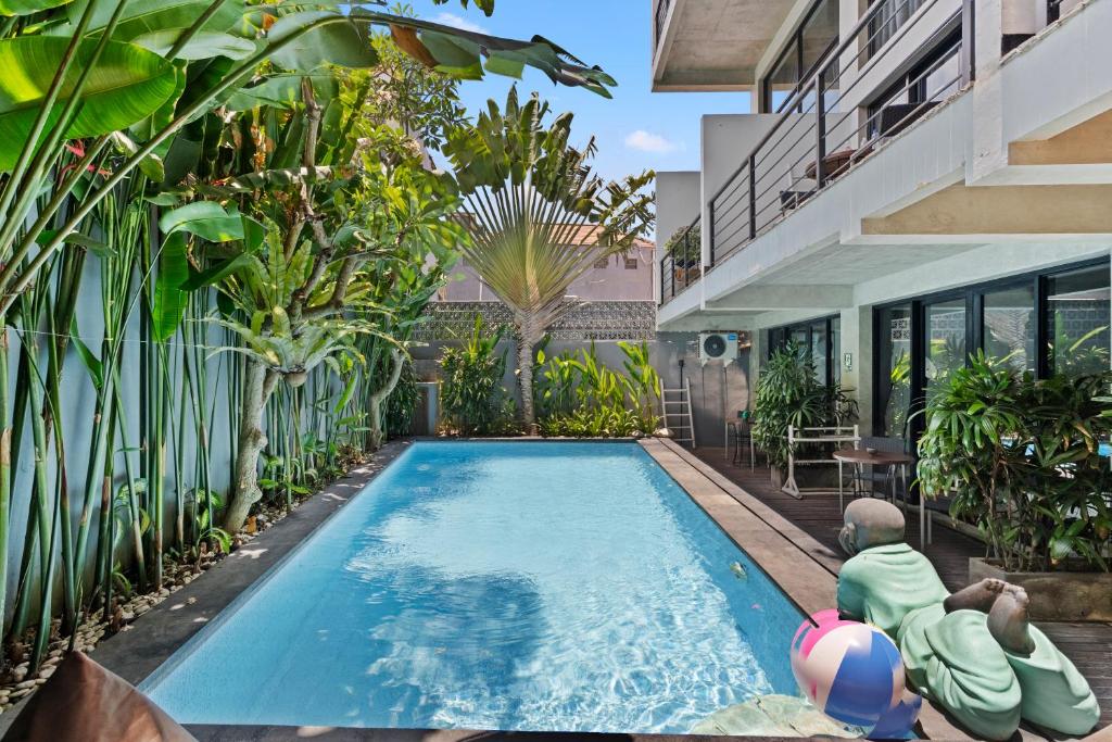 a man sitting on a ball next to a swimming pool at Balissimo Apartment by Hombali in Seminyak