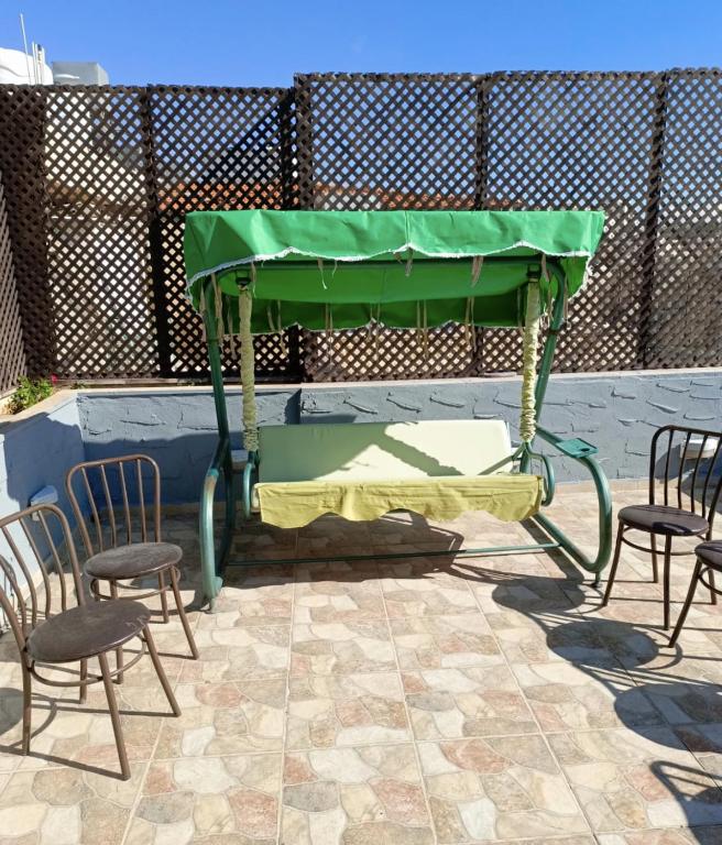 a green table with two chairs and a table at Beautiful 1 bedroom rooftop apartment with a great terrace in Rujm ash Sharāʼirah