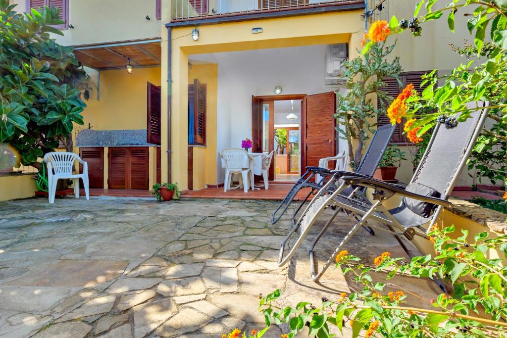 a patio of a house with chairs and tables at Villetta Bougainvillea in San Teodoro