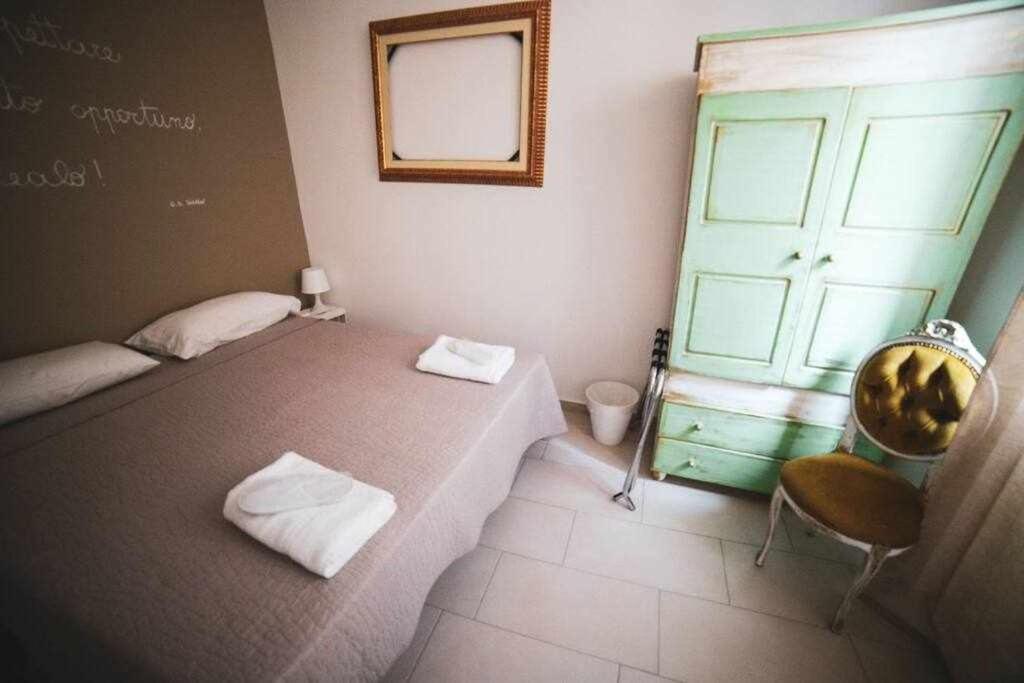 um quarto com uma cama, uma cadeira e uma porta em LE DIMORE DEGLI ARTISTI Vico Mercatello em Venosa