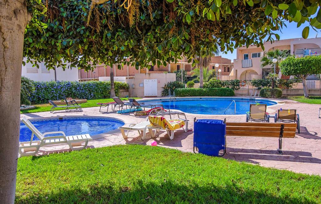 una piscina con un mucchio di sedie accanto ad un albero di II Precioso apartamento con piscina y garaje II a Cuevas del Almanzora