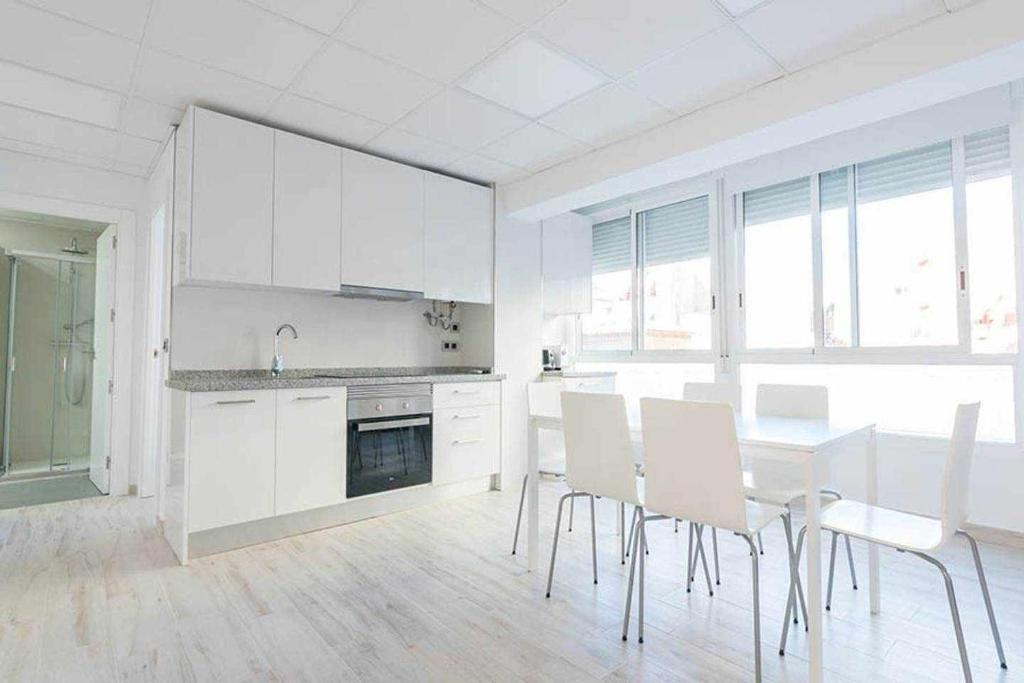 cocina con armarios blancos, mesa y sillas en Apartamentos Arena y Cairo, en Murcia