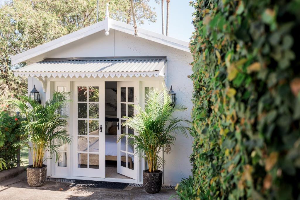 een wit huis met palmbomen ervoor bij Studio 26: Central, Hampton’s Poolside Hideaway in Coffs Harbour