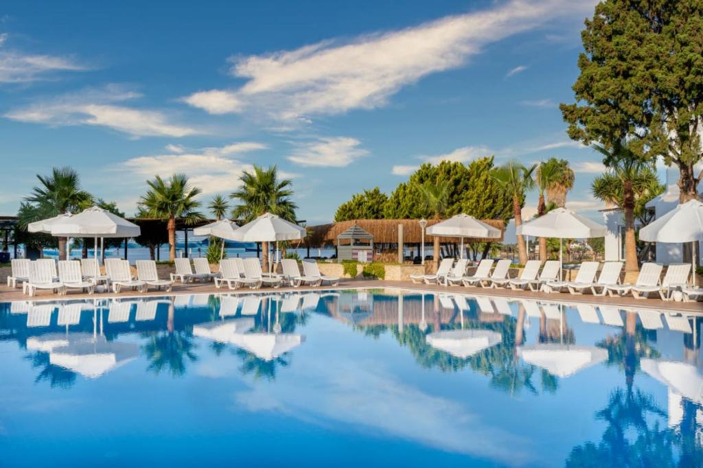 una piscina en un complejo con sillas y sombrillas en Maya World Didyma Hotel, en Didim