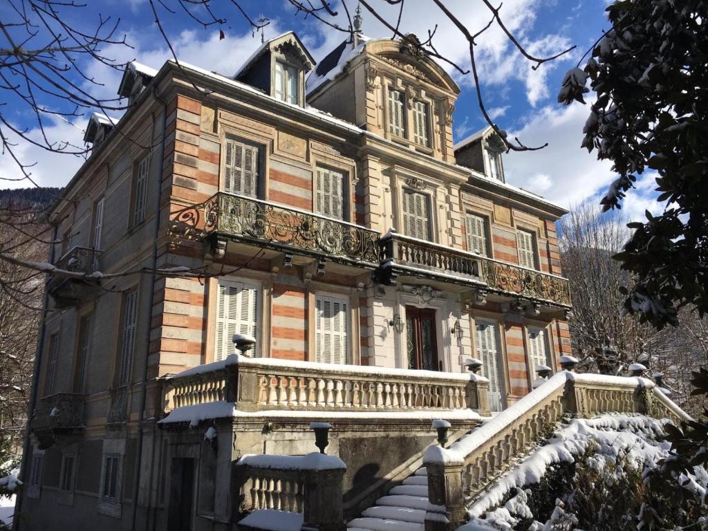 een oud huis met een balkon in de sneeuw bij Villa du Lys in Luchon