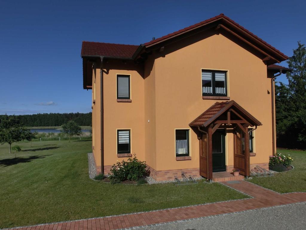 una pequeña casa amarilla con techo marrón en Ferienwohnungen am Federower Hofsee, en Federow