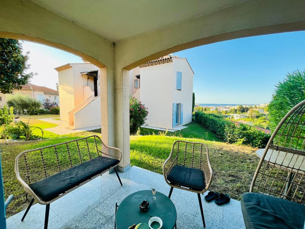 eine Veranda mit 2 Stühlen, einem Tisch und einem Haus in der Unterkunft Beautiful house garden-floor with sea view & 10 min walk in Vallauris