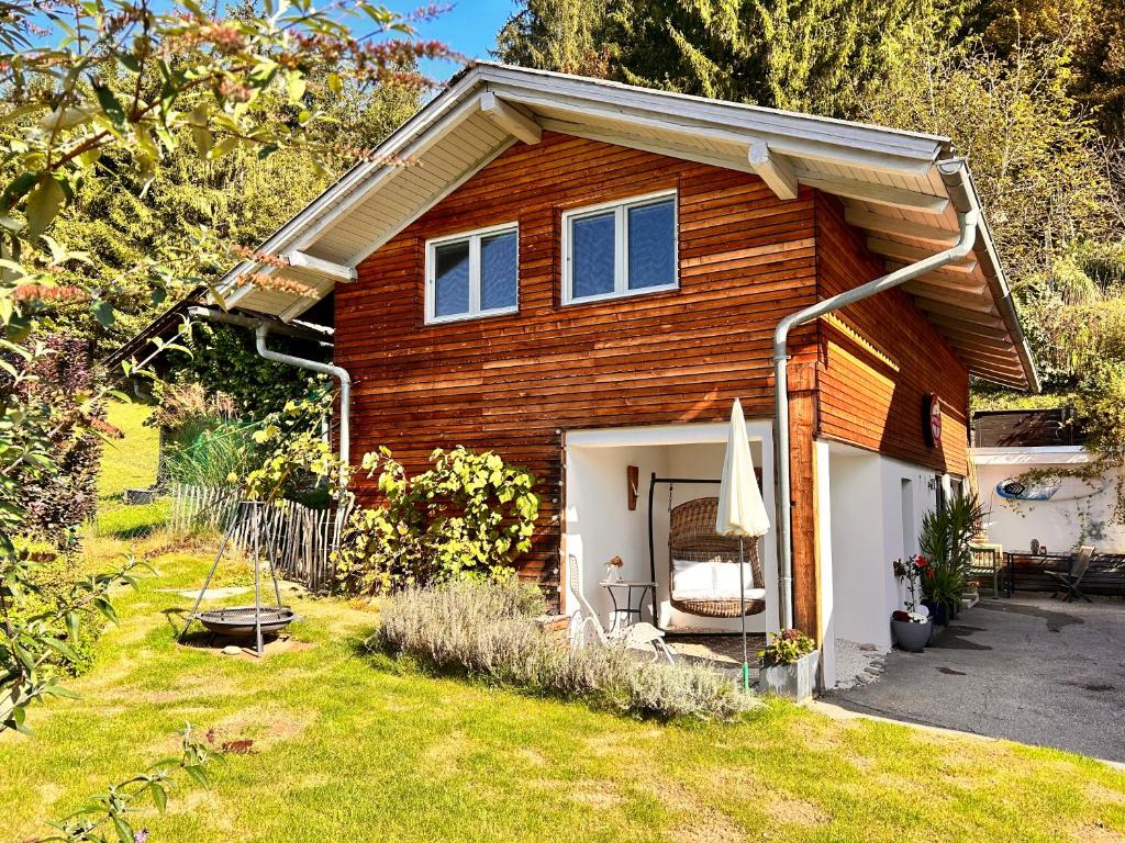 a wooden house with a patio and a yard at Haus an der Drau nahe Velden / App. DRAU byTILLY in Velden am Wörthersee