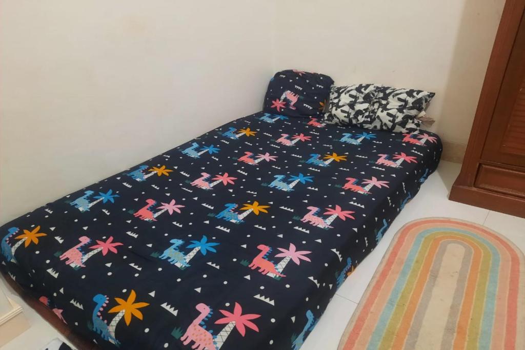 Una cama con un edredón negro con estrellas coloridas en OYO Life 93160 Kost Jenny Karawang, en Karawang