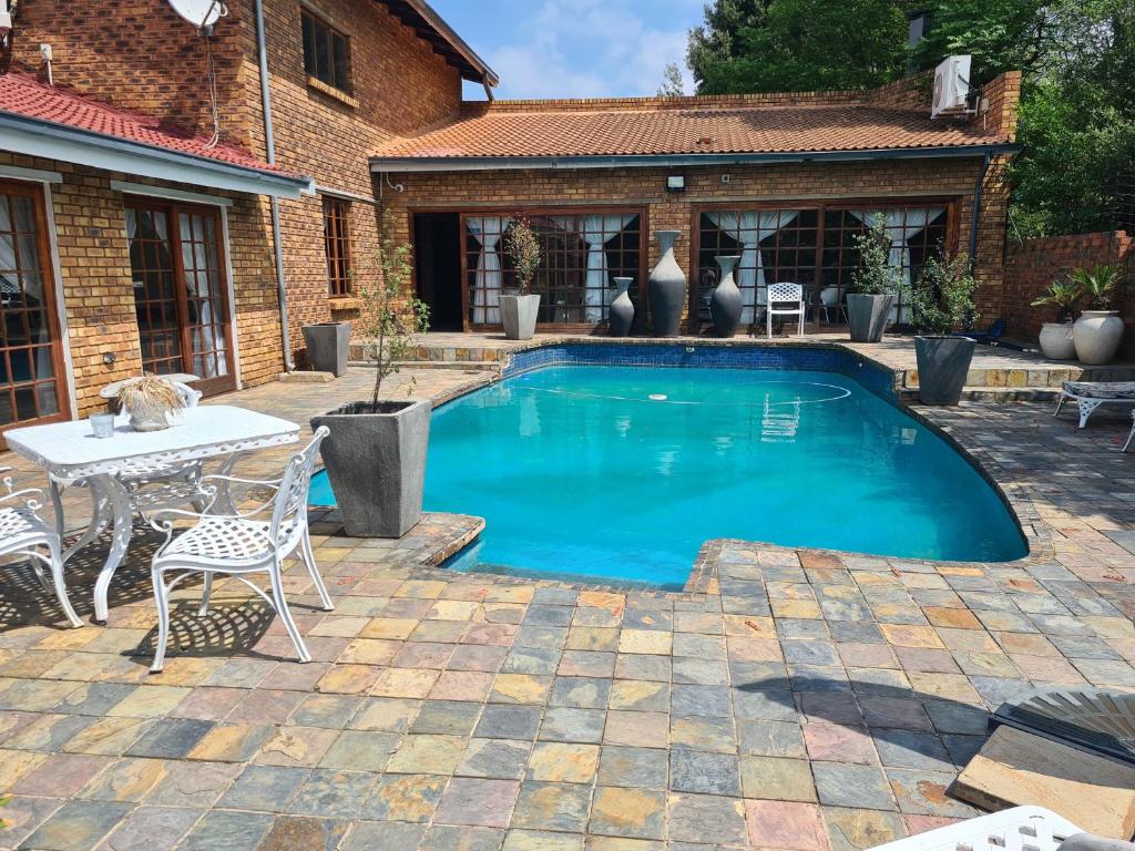 a swimming pool in a yard with a table and chairs at Royal Villa Guesthouse in Brakpan