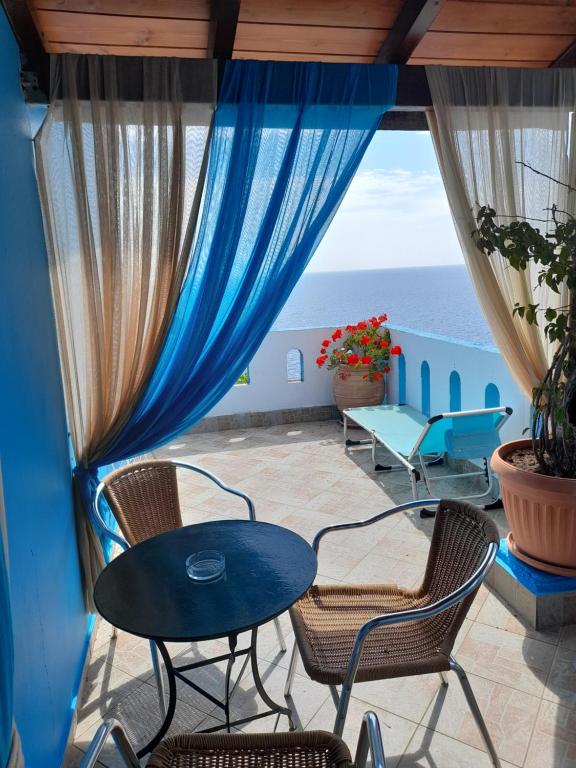 balcón con mesa, sillas y vistas al océano en Delfini, en Akhladherí