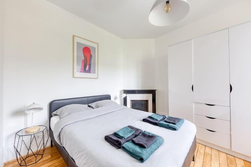 a white bedroom with a bed with two towels on it at Appartement entier au coeur de Nogent Sur Marne in Nogent-sur-Marne