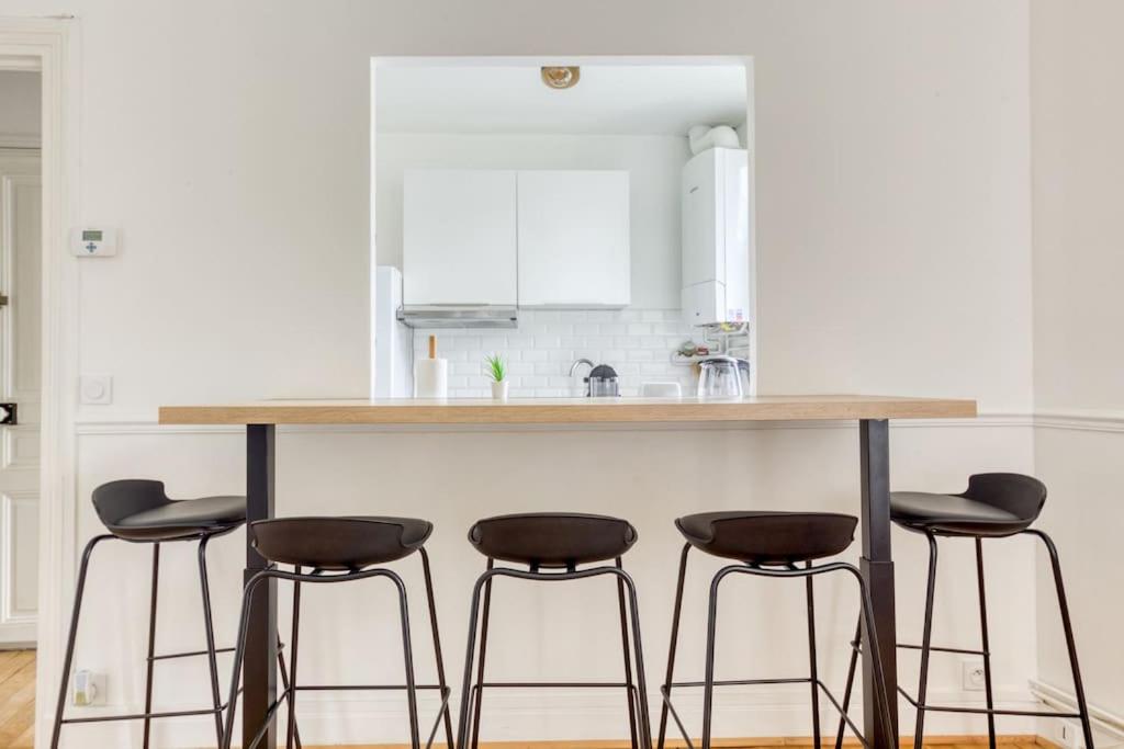 a kitchen with a counter with four bar stools at Appartement entier au coeur de Nogent Sur Marne in Nogent-sur-Marne
