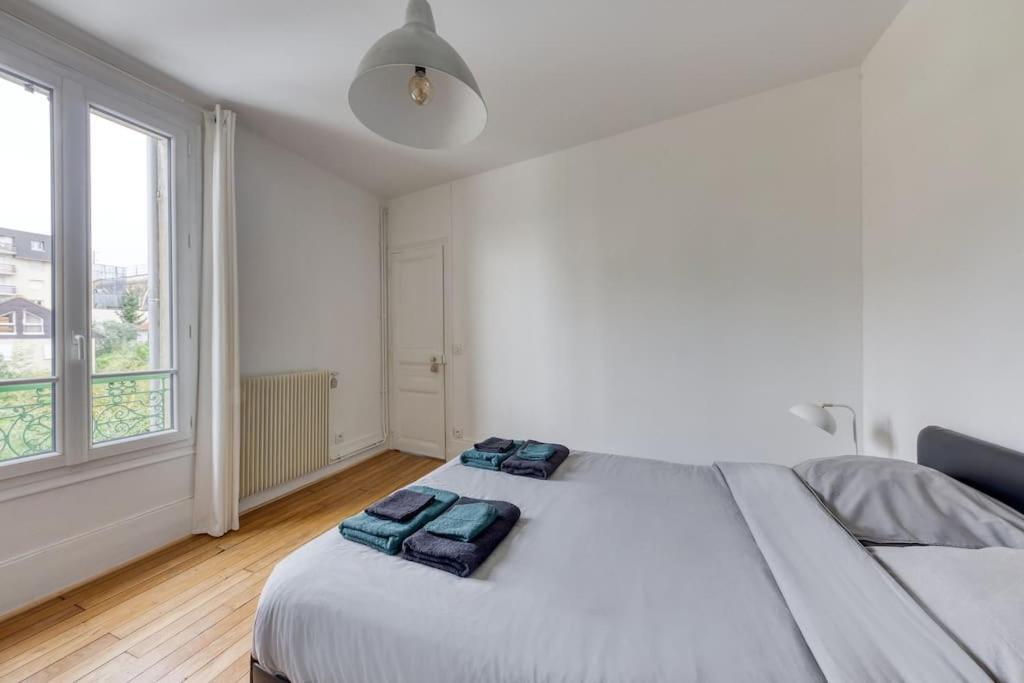 a white bedroom with a bed with two blue towels on it at Appartement entier au coeur de Nogent Sur Marne in Nogent-sur-Marne