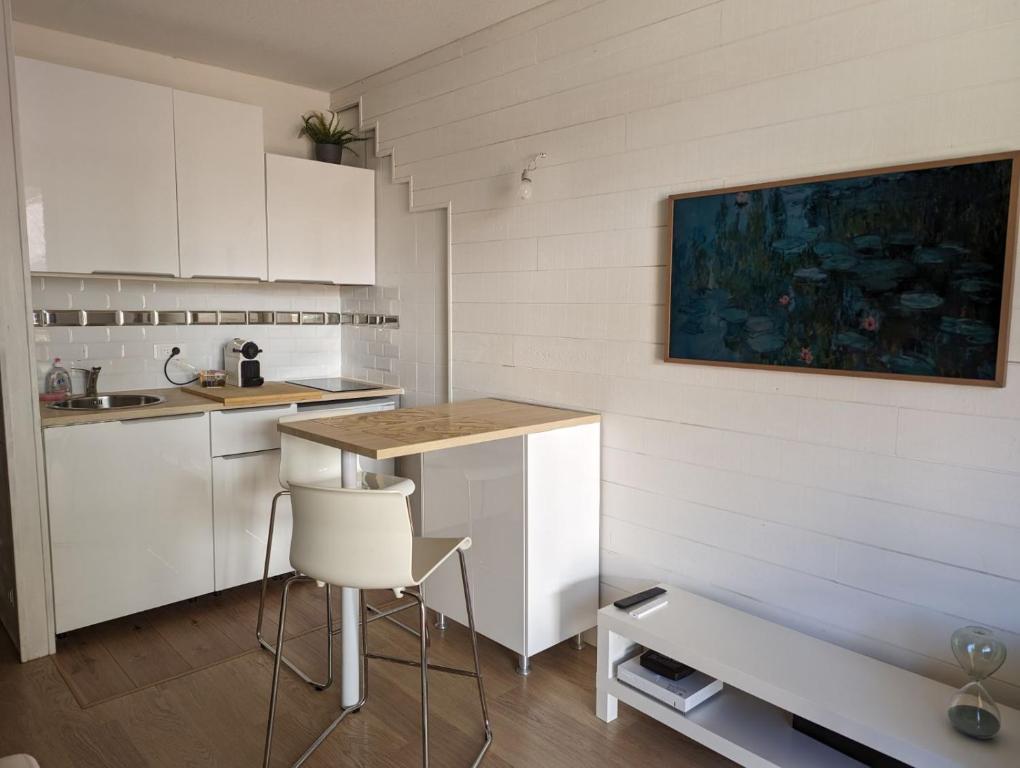 a kitchen with white cabinets and a table and a chair at Studio hyper centre in Luchon
