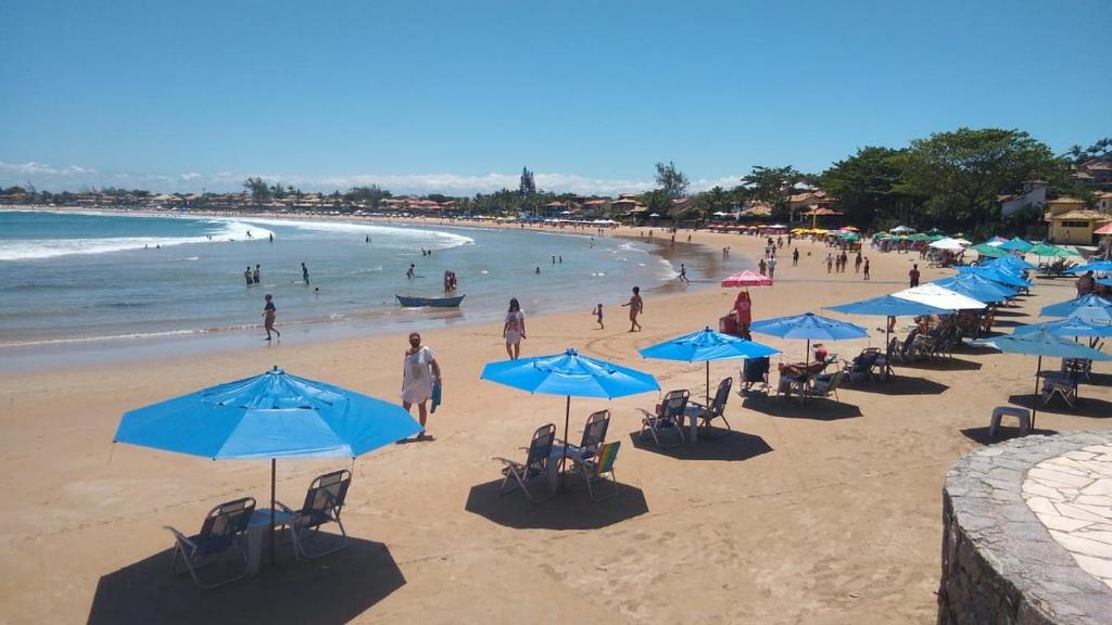 a beach with blue umbrellas and people on the beach at Praia de Geribá 100m - loft no corredor de acesso a praia in Búzios