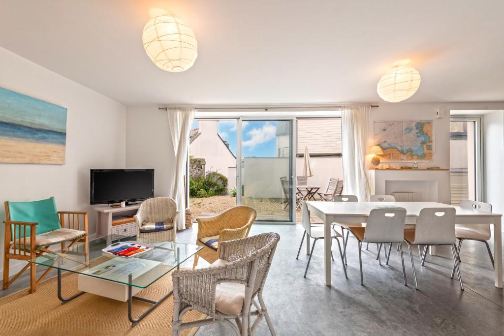 un salon avec une table, des chaises et une télévision dans l'établissement Grande maison sur le port, à Locquirec