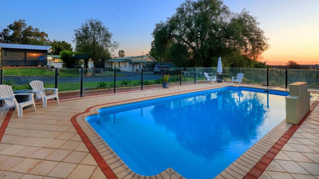 een zwembad met blauw water in een tuin bij Oasis Motel in Peak Hill