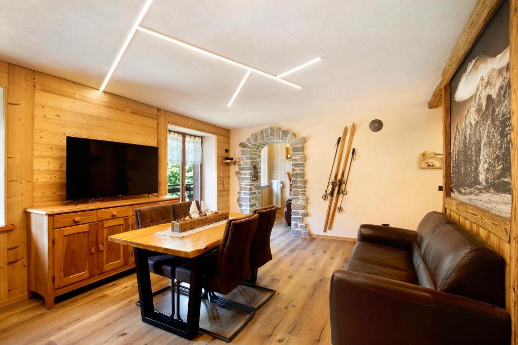 a living room with a table and a television at Aiguille Noire La Maison de Courma in Courmayeur