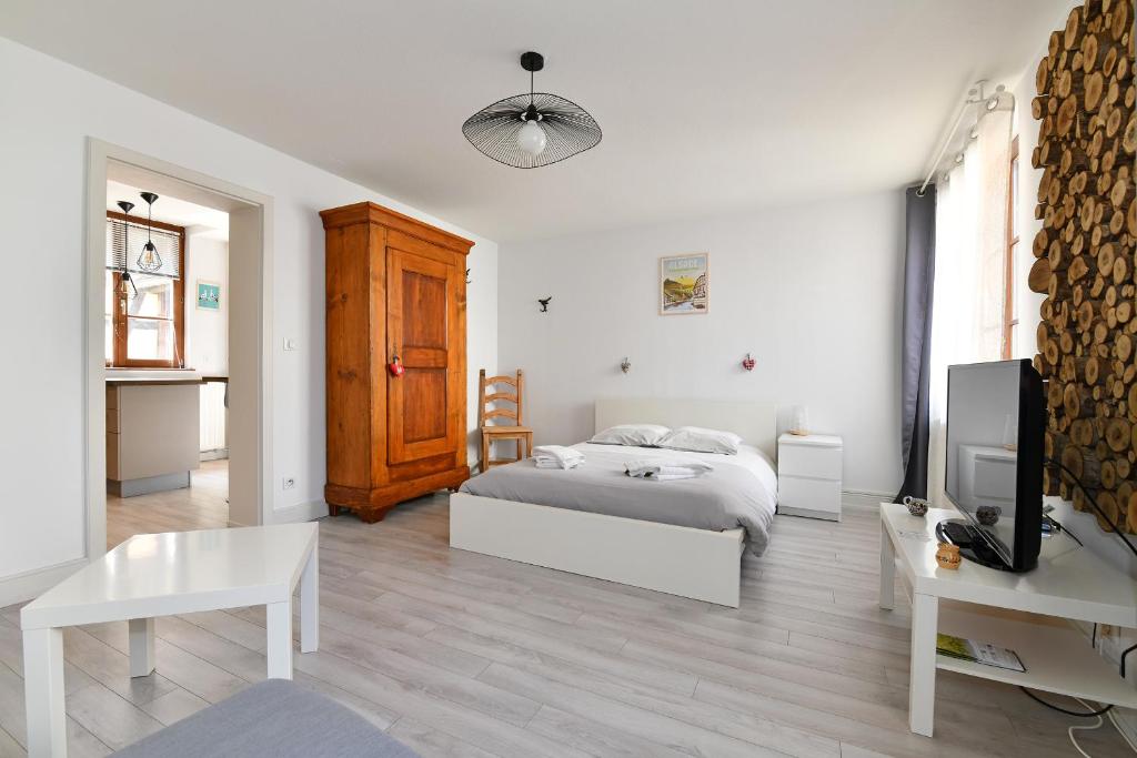 um quarto branco com uma cama e uma televisão em Jaennette em Ribeauvillé