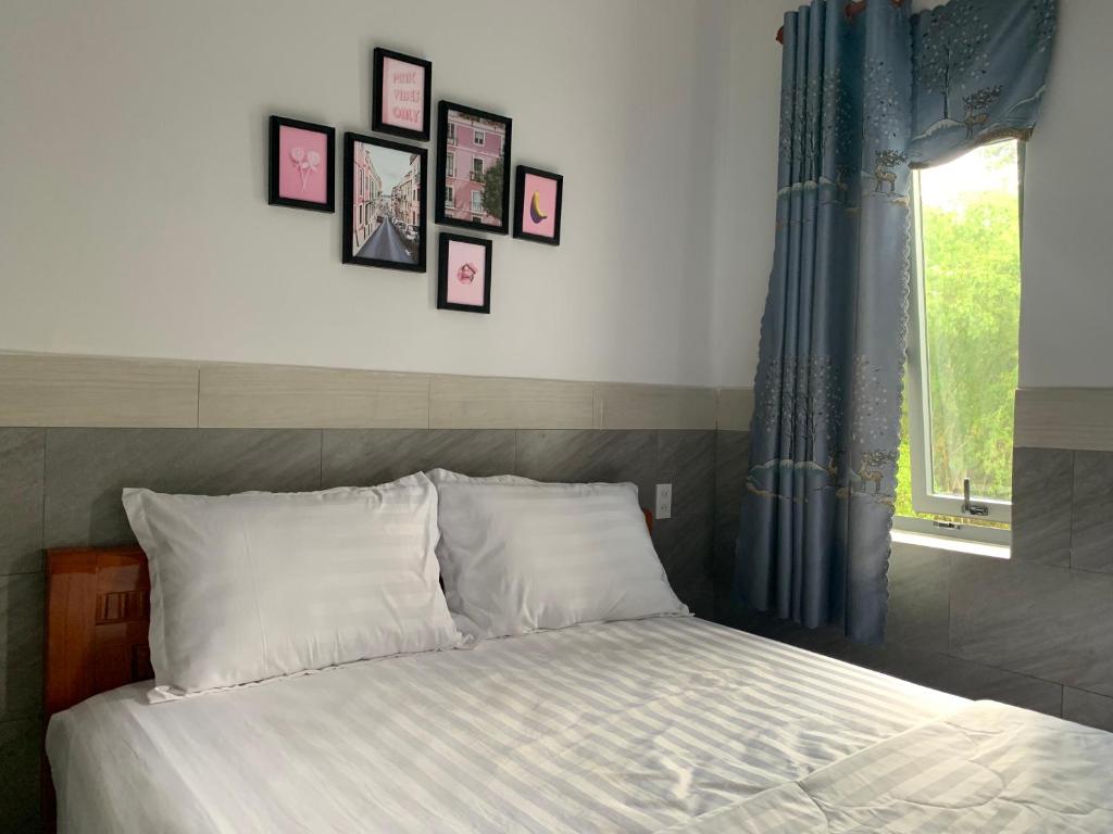 1 dormitorio con 1 cama con cuadros en la pared en Khách Sạn An Bình en Phước Lộc Xã