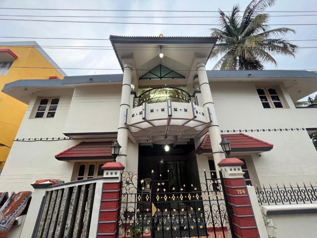 een wit huis met een poort en een balkon bij N A S HOMESTAY in Mysore