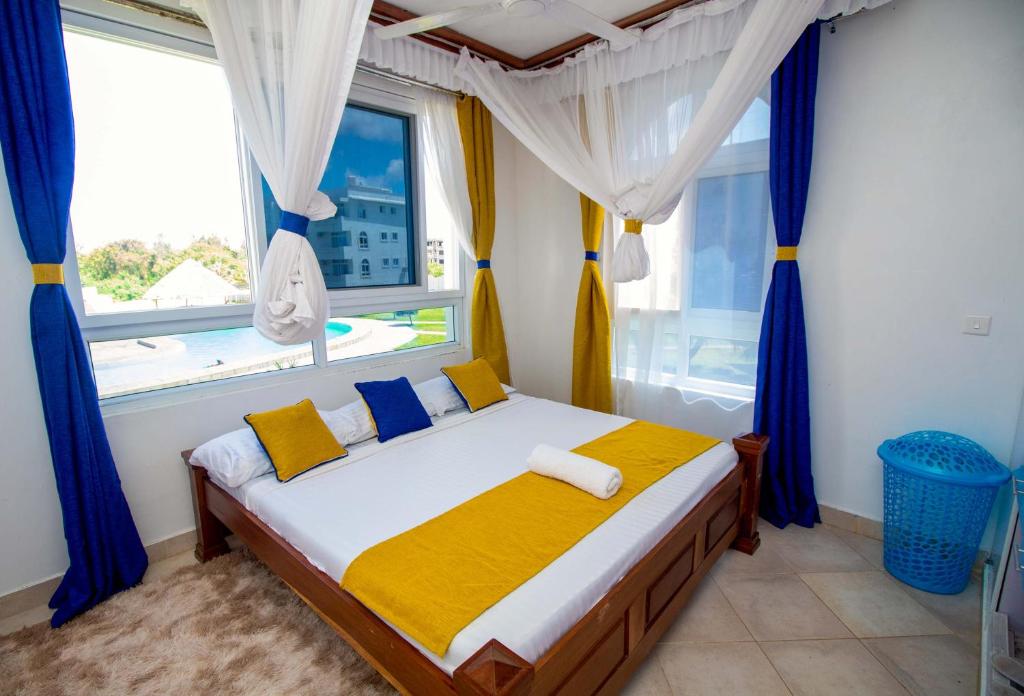 a bedroom with a bed with blue curtains and a window at Kijani Suites in Malindi