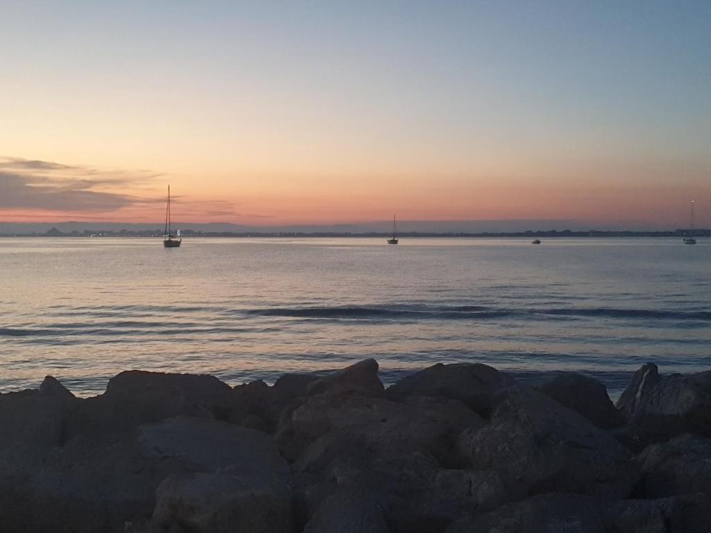 un coucher de soleil sur l'océan avec des bateaux dans l'eau dans l'établissement La petite Camargue, au Grau-du-Roi