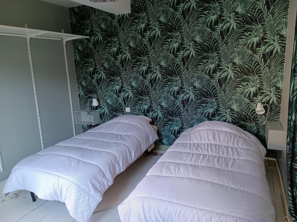 two beds in a bedroom with a green wall at Auberge des chemins in Moissac
