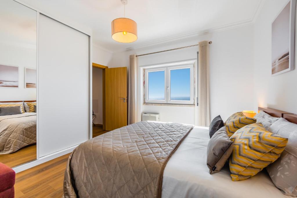 ein Schlafzimmer mit einem Bett und einem großen Spiegel in der Unterkunft Ericeira Vista Mar Peace and Sea in Ericeira