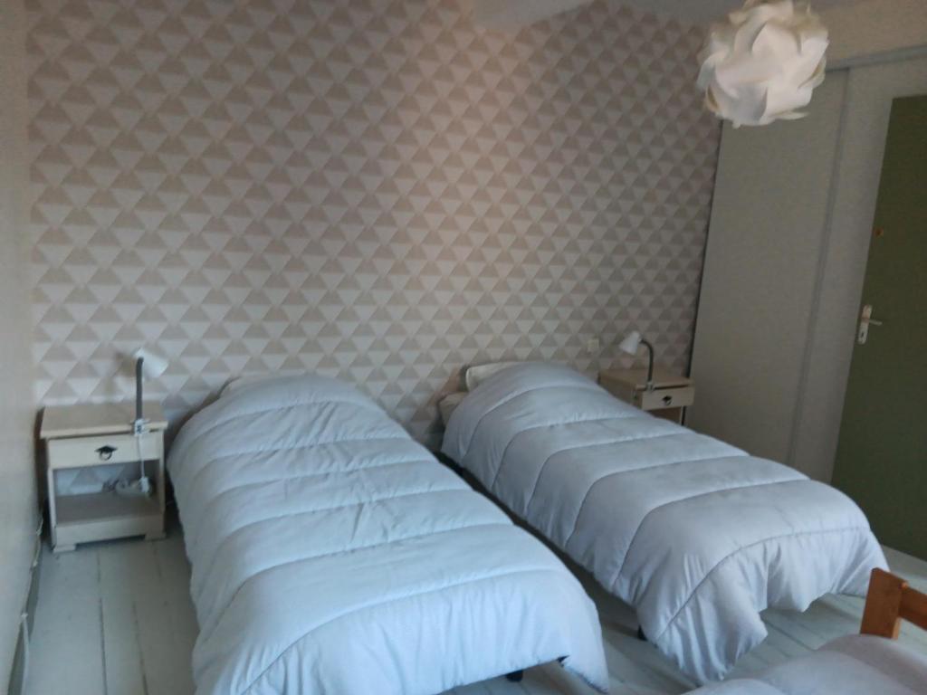 a bedroom with three beds and a wall with wallpaper at Auberge des chemins in Moissac
