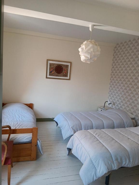 a room with three beds and a pendant light at Auberge des chemins in Moissac