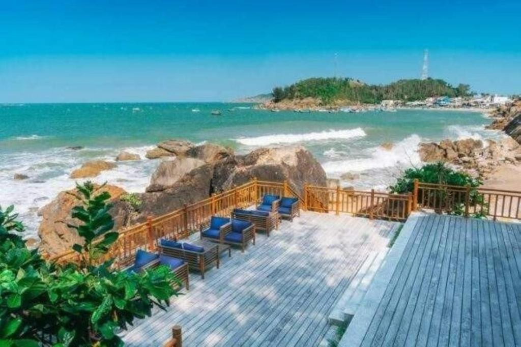 a boardwalk leading to a beach with blue chairs at Resort Bai Xep Quy Nhon in Quy Nhon