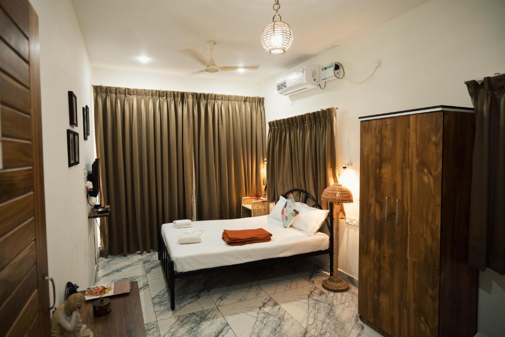 a bedroom with a bed and a lamp and curtains at Nirvana Homestays in Siolim