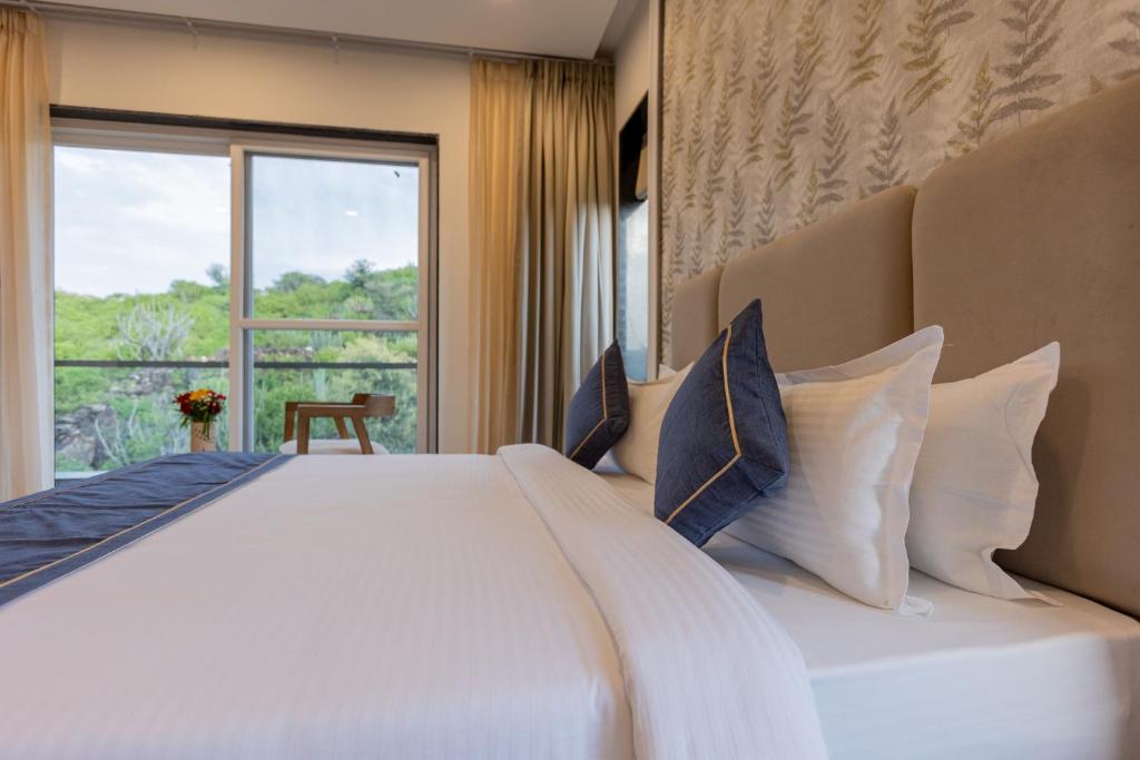 a bedroom with a large white bed with a window at SURAMYA-A Luxury Boutique Hotel in Udaipur