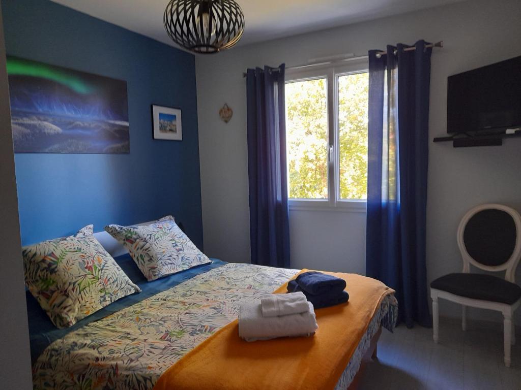 um quarto com uma cama com paredes azuis e uma janela em La Zénitude chambre d hôte em Chamarandes