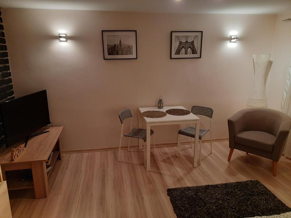 ein Wohnzimmer mit einem Tisch und Stühlen sowie einem TV in der Unterkunft Villa Belveder in Posen