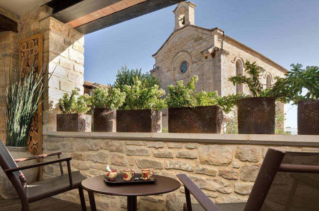 une terrasse avec une table, des chaises et une église dans l'établissement La Maison du Passage - Chambres - Suites premium, Spa, Piscine et Restaurant, à Martignargues