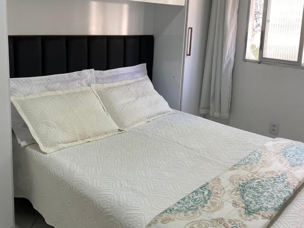 Una cama con sábanas blancas y almohadas en un dormitorio en Host dos Anjos, en Arraial do Cabo